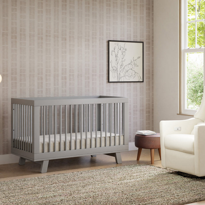 Babyletto Hudson 3-in-1 Crib next to a recliner and window  in -- Color_Grey