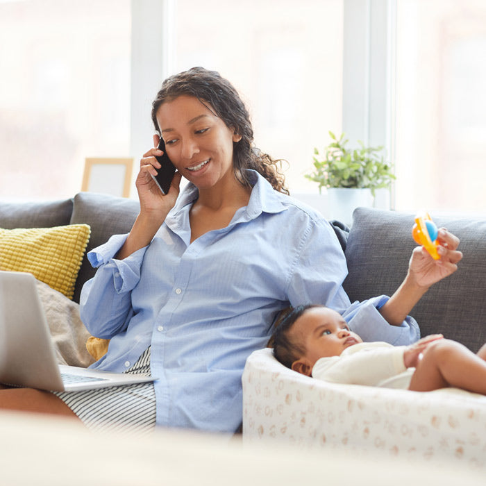 woman talking on phone while entertaining infant with toy
