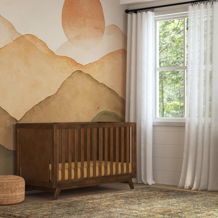 DaVinci Otto 3-in-1 Convertible Crib next to a window in -- Color_Walnut _ Wood