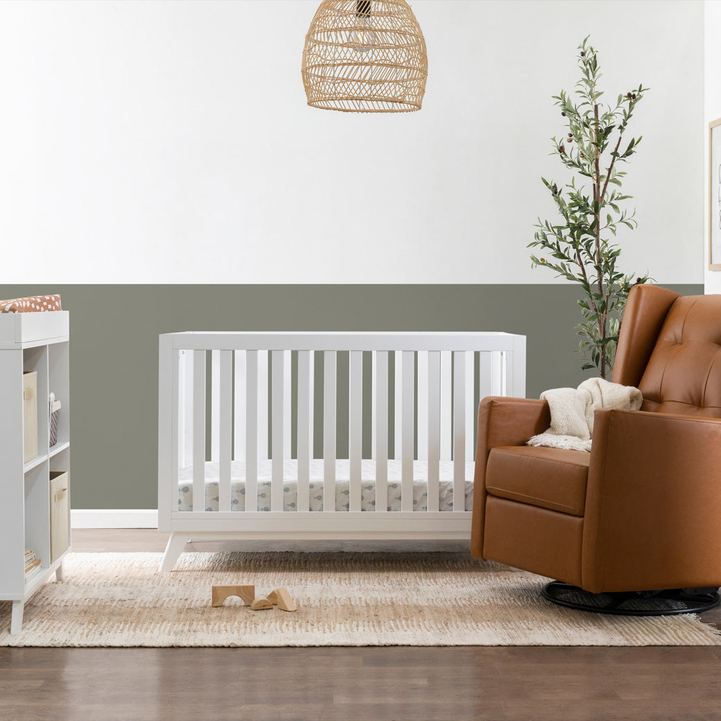 DaVinci Otto 3-in-1 Convertible Crib next to a recliner  in -- Color_White _ Wood