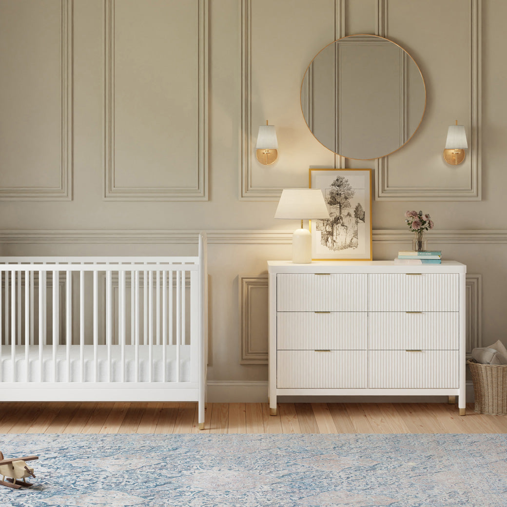 Front view of Namesake Brimsley 6-Drawer Dresser next to a crib in -- Color_Warm White