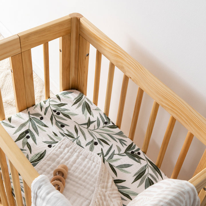 Babyletto All-Stages Bassinet Sheet In GOTS Certified Organic Muslin Cotton in a crib with a toy in -- Color_Olive Branches