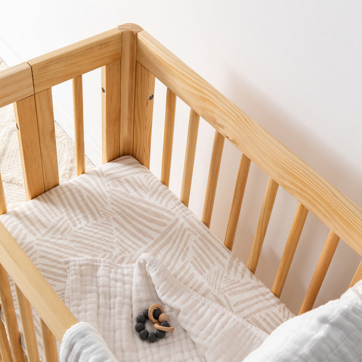 Babyletto All-Stages Bassinet Sheet In GOTS Certified Organic Muslin Cotton in a crib with a toy in -- Color_Oat Stripe