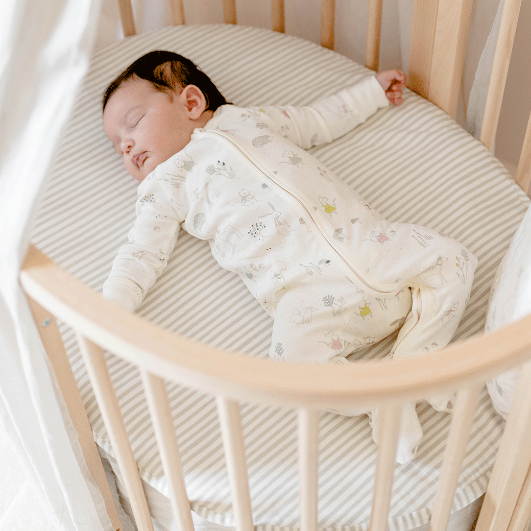 Baby in a crib sleeping on Stokke's Sleepi V3 Mini Fitted Sheet By Pehr in -- Color_Stripes Away Pebbles