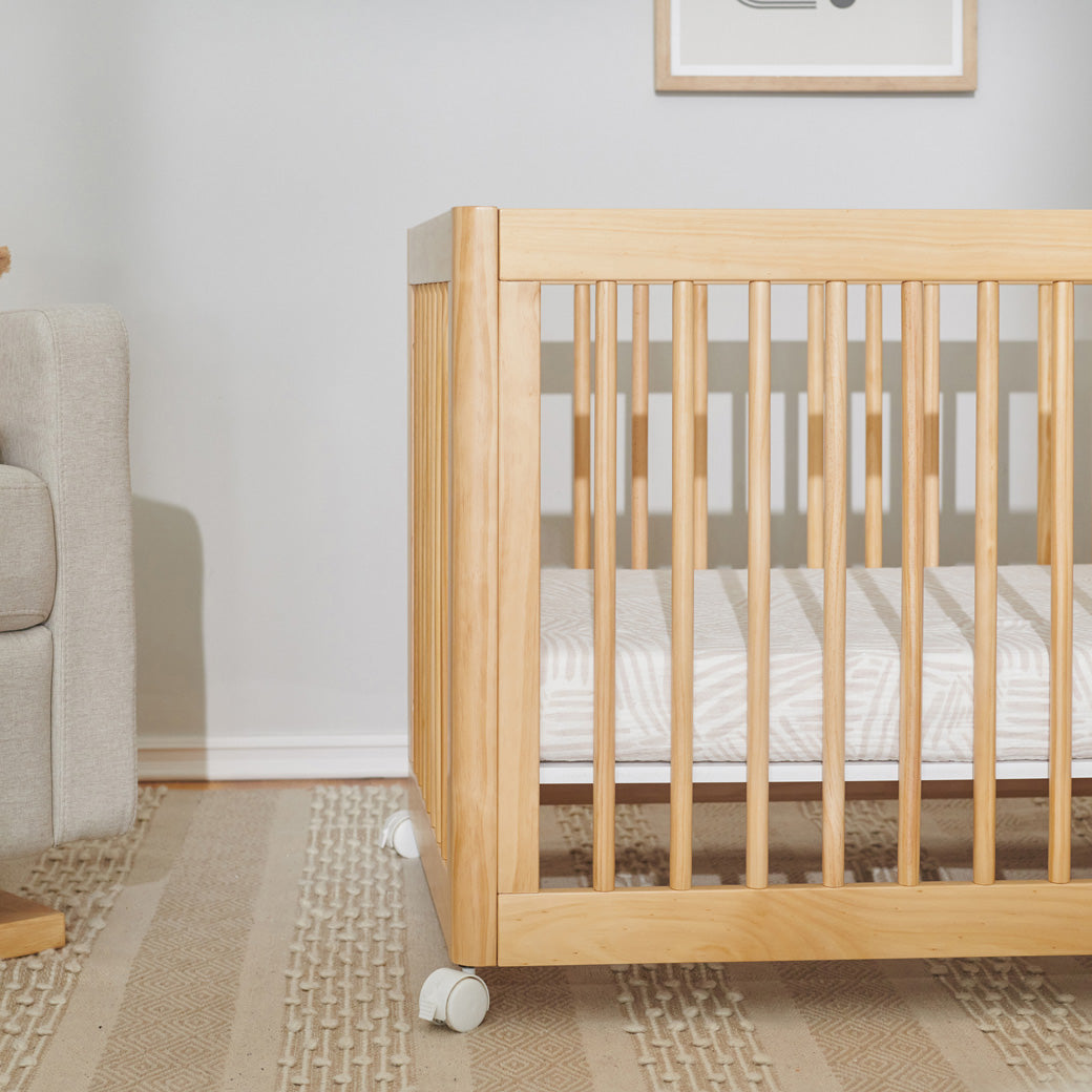 Closeup of crib equipped with Babyletto's All-Stages Midi Crib Sheet In GOTS Certified Organic Muslin Cotton in -- Color_Oat Stripe