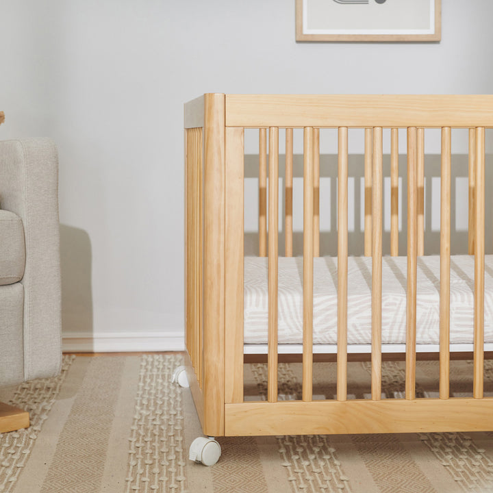 Closeup of crib equipped with Babyletto's All-Stages Midi Crib Sheet In GOTS Certified Organic Muslin Cotton in -- Color_Oat Stripe