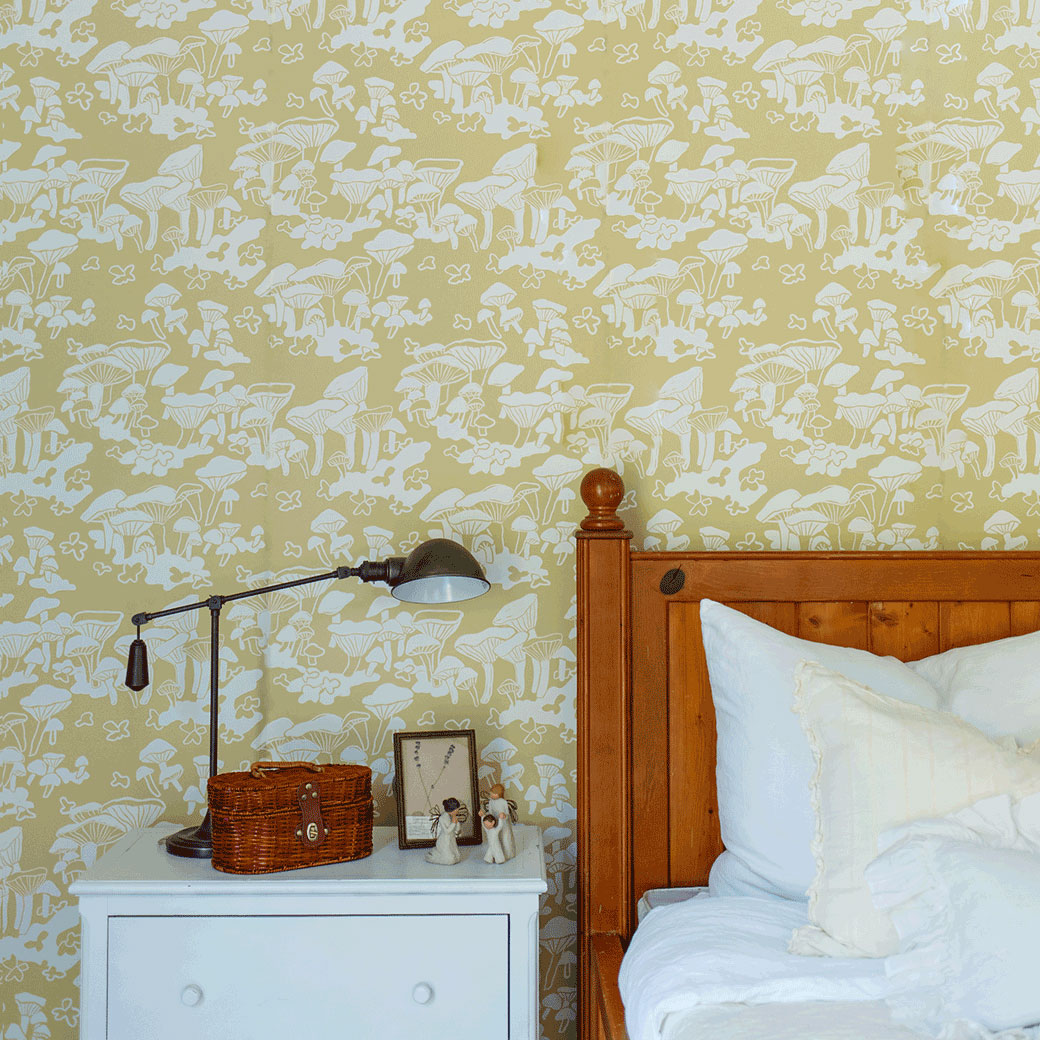 Closeup of nightstand and bed frame next to the Anewall Forest Floor Mushroom Wallpaper